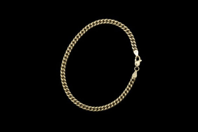 May include: A gold chain bracelet with a curb link design. The bracelet has a lobster claw clasp.