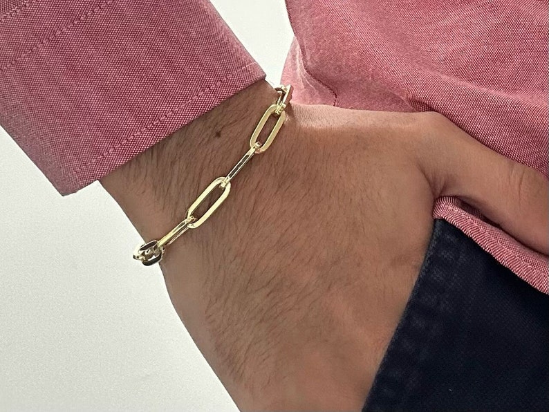 May include: A gold chain bracelet with oval links. The bracelet is worn on a person's wrist.