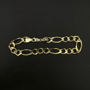 May include: A gold chain bracelet with a figaro link pattern.