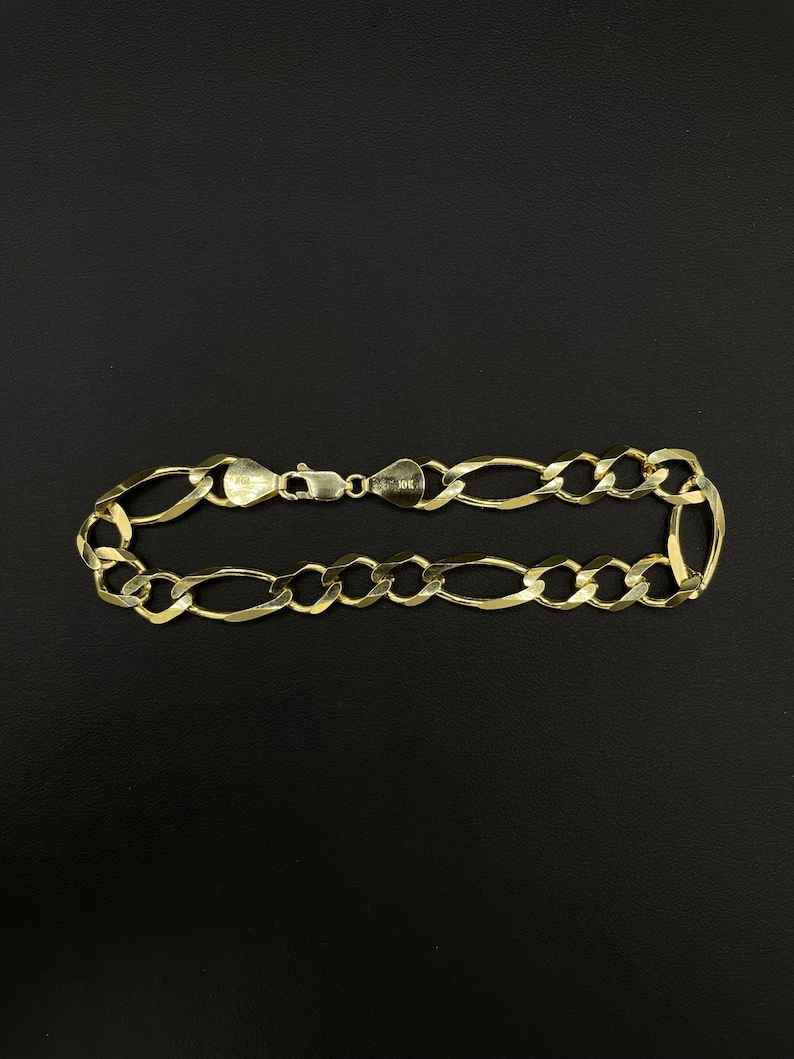May include: A gold chain bracelet with a figaro link pattern.