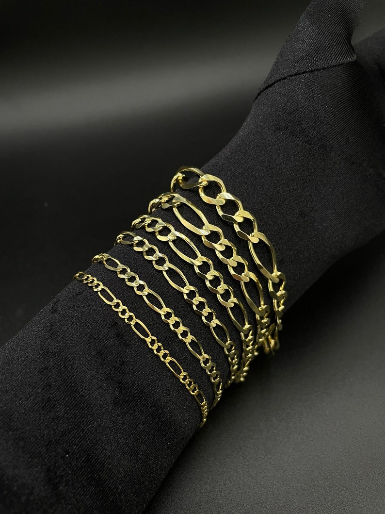 May include: A set of gold chain bracelets of varying widths and lengths. The chains are all made of a classic, flat, curb link design.