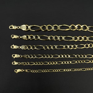 May include: Six gold chains of different lengths and widths, all with a classic figaro design. The chains are laid out in a row on a black background.