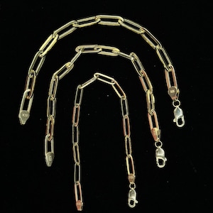 May include: Three gold chain necklaces with different lengths. The chains are made of oval-shaped links. The chains have lobster claw clasps.