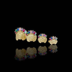 May include: Three gold rings with colorful gemstones set in the shape of a Native American chief's head. The rings are different sizes.