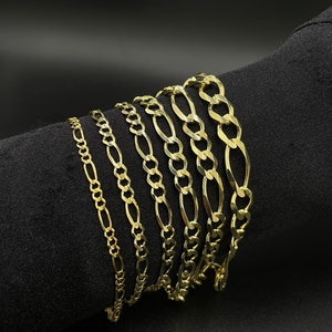 May include: A set of seven gold chain bracelets of varying widths and lengths. The chains are all made of a classic, flat, oval-shaped link.