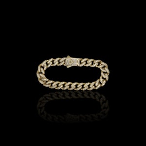 May include: A gold chain bracelet with a diamond-encrusted design. The bracelet has a clasp closure.