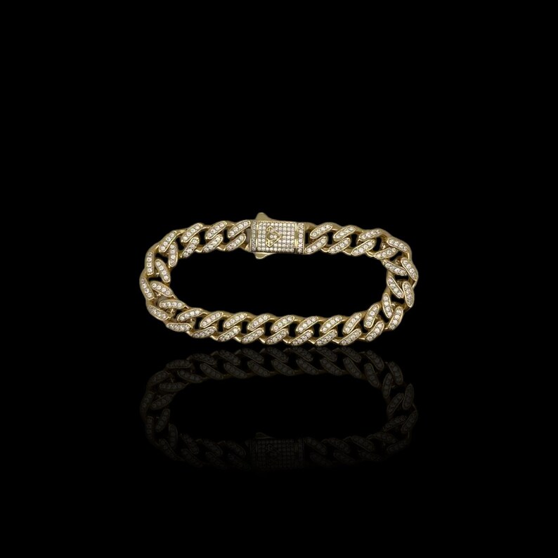 May include: A gold chain bracelet with a diamond-encrusted design. The bracelet has a clasp closure.
