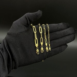 May include: Five gold chain necklaces with different lengths and link styles. The chains are displayed on a black fabric background.