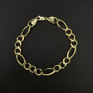 May include: A gold chain bracelet with a 10K stamp. The bracelet is made of a thick, oval-shaped chain.