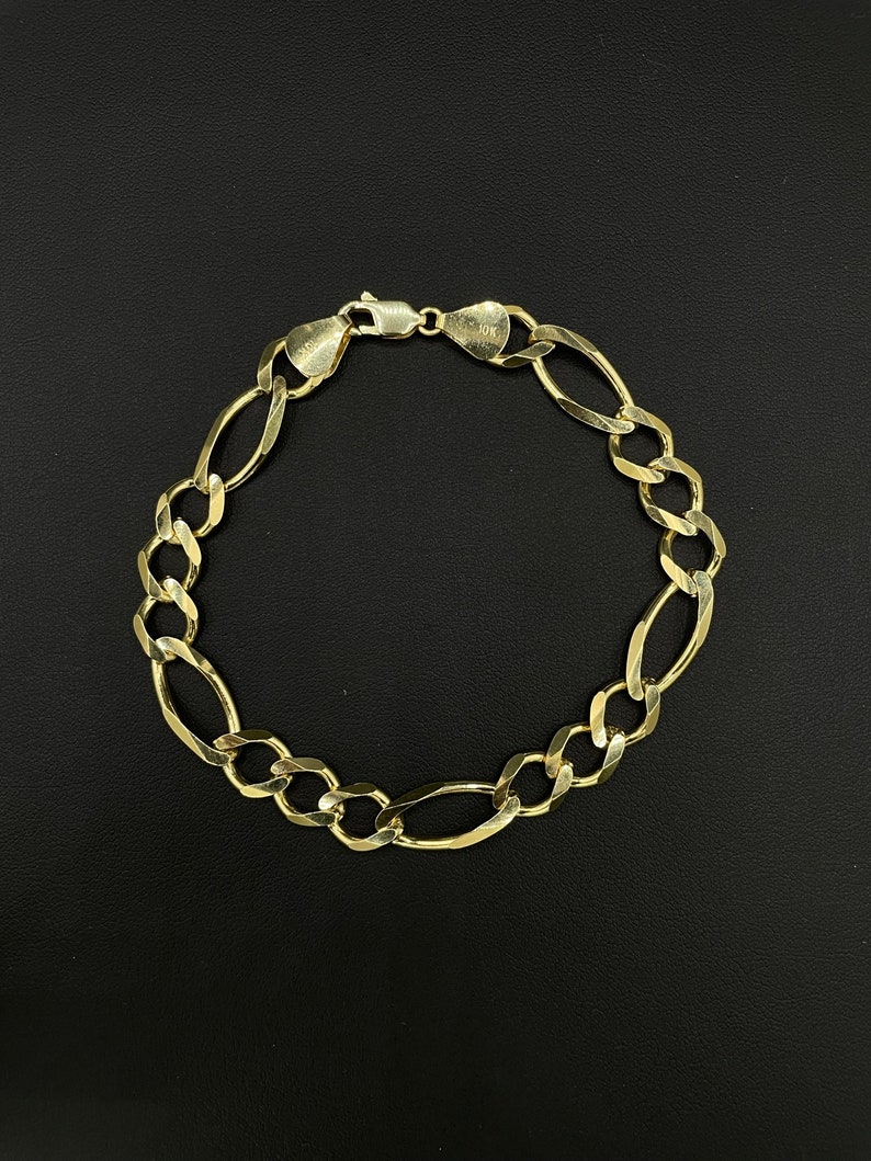 May include: A gold chain bracelet with a 10K stamp. The bracelet is made of a thick, oval-shaped chain.