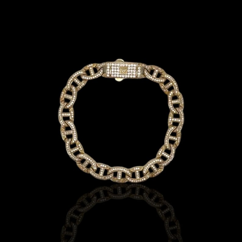 May include: A gold chain bracelet with a mariner link design. The bracelet is set with small, clear diamonds.