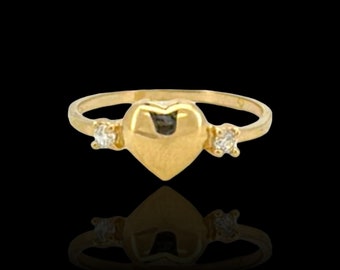 Könnte beinhalten: Ein goldener Ring mit einem herzförmigen Zentrum und zwei kleinen, klaren Steinen auf jeder Seite.