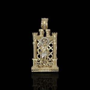 May include: A gold pendant featuring a detailed depiction of a religious figure standing within a decorative, ornate frame.