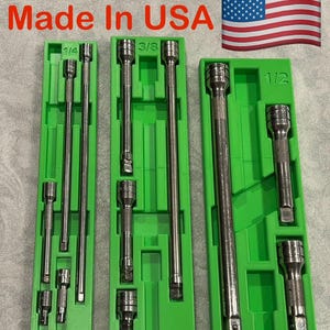 May include: A set of chrome socket extensions and sockets in green plastic trays. The sizes are 1/4, 3/8, and 1/2 inch. The text "Made In USA" is above the trays, with an American flag in the background.