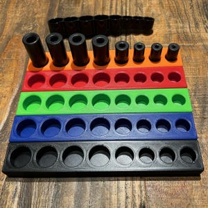 May include: A multi-colored tool organizer with black cylindrical objects. The organizer has five tiers in black, blue, green, red, and orange. The top tier holds black cylindrical objects of varying sizes. The organizer is designed to hold tools.