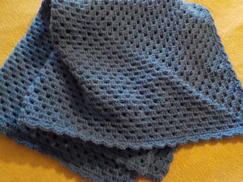 Peut inclure: Une couverture en crochet bleu avec un bord festonn&eacute;. La couverture est r&eacute;alis&eacute;e avec un point textur&eacute;.