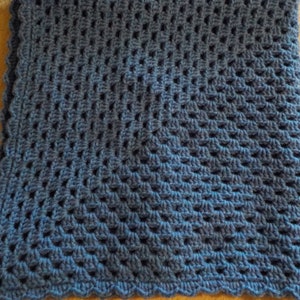 Peut inclure: Une couverture en crochet bleue avec un bord festonn&eacute;. La couverture est r&eacute;alis&eacute;e avec un motif de points textur&eacute;s.