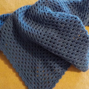 Peut inclure: Une couverture en crochet bleu avec un bord festonn&eacute;. La couverture est r&eacute;alis&eacute;e avec un motif de point simple et est douce et confortable.