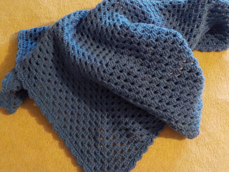 Peut inclure: Une couverture en crochet bleu avec un bord festonn&eacute;. La couverture est r&eacute;alis&eacute;e avec un motif de point simple et est douce et confortable.