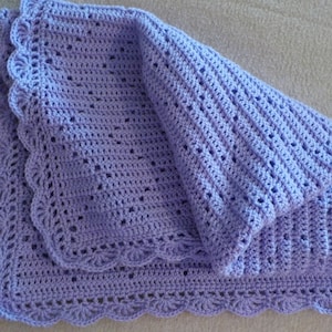 Peut inclure: Une couverture pour bébé en crochet de couleur lavande avec un bord festonné.