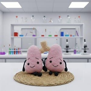 May include: Two pink crocheted lung-shaped plush toys with black arms and legs, and smiling faces, sit on a round woven mat. A beige crocheted trachea is between them. The background is a lab setting with beakers and microscopes.