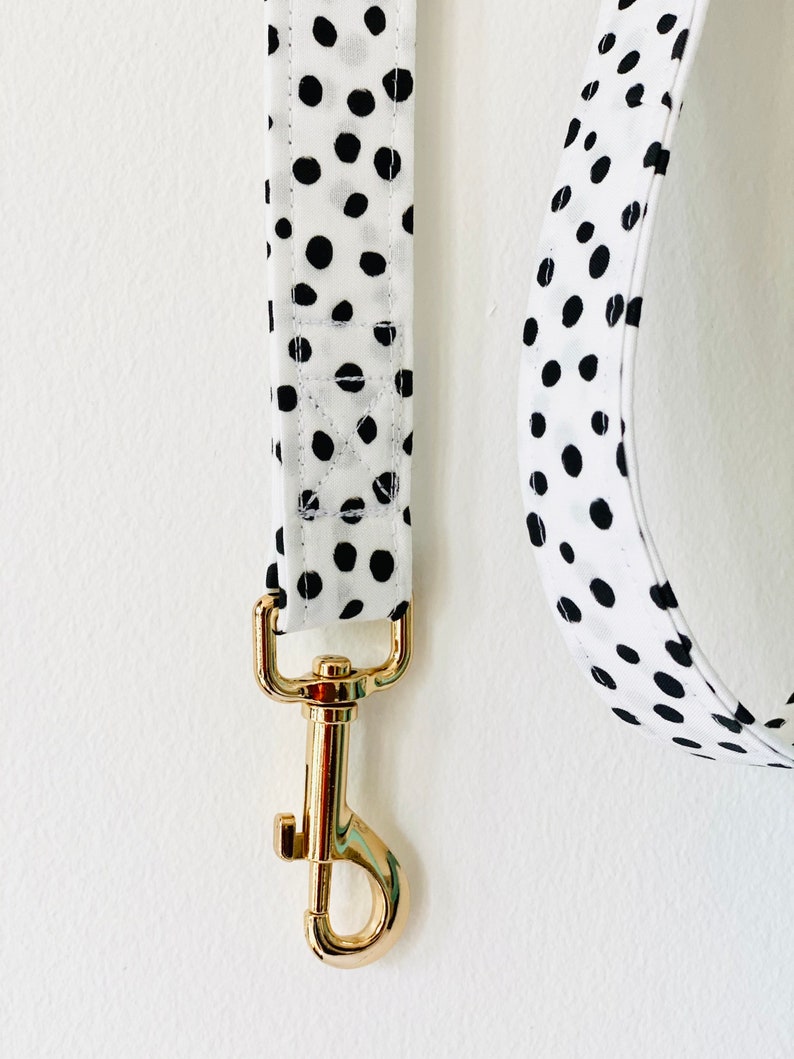 May include: A white and black polka dot dog leash with a gold metal clasp.