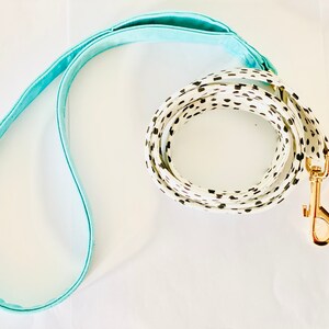 May include: A white and black polka dot dog leash with a light blue handle and a gold metal clasp.