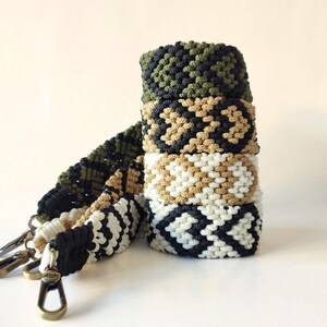 May include: A set of four woven straps in black, white, green, and brown patterns. The straps are made of a thick, durable cord and have a woven design. The straps are connected to metal clasps.