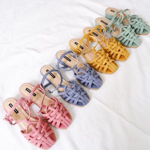 K&ouml;nnte beinhalten: Sechs Paar geflochtene Sandalen mit Absatz in verschiedenen Farben, darunter Rosa, Blau und Gelb. Die Sandalen haben ein geflochtenes Design und einen dicken Absatz.