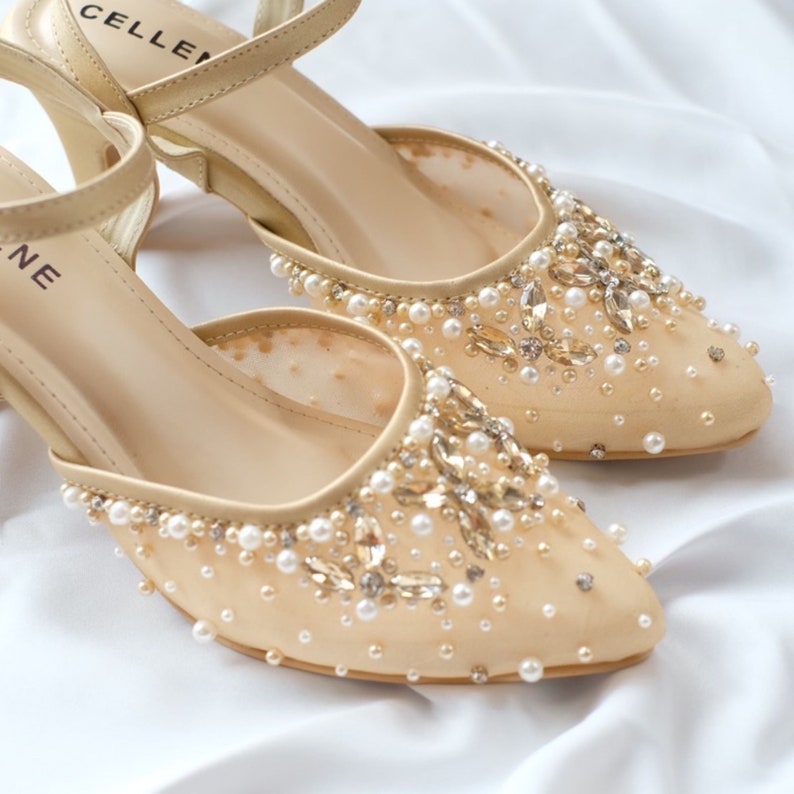 May include: A pair of beige mesh heeled shoes with a pointed toe and embellished with pearls and rhinestones.