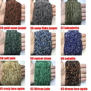 May include: A collection of 9 strands of gemstone beads, each strand is a different color and type of stone. The beads are small and round, and they are arranged in a grid pattern. The stones include gold swan jasper, snow flake jasper, labradorite, soft jade, sunset stone, sodalite, crazy lace agate, African jade, and dream lace agate.