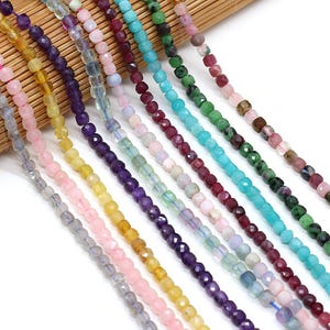 May include: Multiple strands of faceted gemstone beads arranged in parallel rows. The beads feature a variety of colours including grey, pink, yellow, purple, iridescent blue, light pink, deep red, turquoise, green, and mottled pink and green.