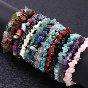 Pode incluir: Uma pilha de pulseiras de pedra de chip em várias cores, incluindo rosa, verde, azul, vermelho e preto.