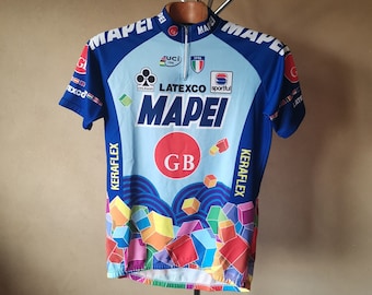 Może przedstawiać: Niebiesko-biała koszulka kolarska z kolorowym geometrycznym wzorem. Koszulka ma napis "MAPEI" i "LATEXCO" z przodu. Koszulka ma również litery "GB" na białym kole.