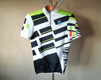 May include: A white, black, and green cycling jersey with a geometric pattern. The jersey has a half-zip closure and a small blue logo on the chest.