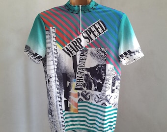 May include: A short-sleeved cycling jersey with a colorful design. The jersey features a teal, blue, and red striped pattern, with the words "WARP SPEED" and "CHARACTER" printed on the front. The jersey has a zipper and a high collar.
