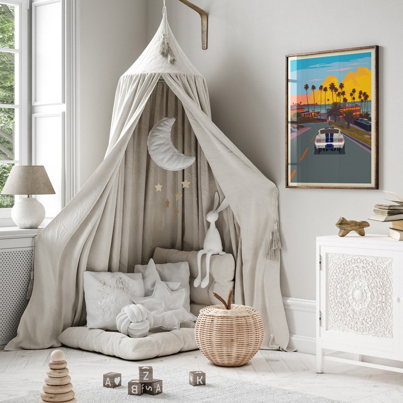 K&ouml;nnte beinhalten: Ein wei&szlig;es Tipi-Zelt mit einem wei&szlig;en Stofftier-Hasen, einem Weidenkorb und einem wei&szlig;en Kissen mit einem Knotendesign. Das Tipi ist mit einem Halbmond und Sternen verziert. Ein gerahmtes Poster mit einer Sonnenuntergangsszene und einem Auto h&auml;ngt an der Wand.