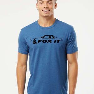 May include: Blue crew neck t-shirt with a black graphic of a car and the text "FOX IT". The graphic features a stylized fox head. The shirt is made of a soft, comfortable material.