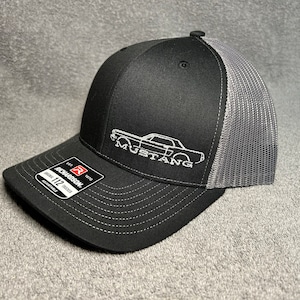 May include: Black and grey trucker hat with a white embroidered outline of a classic Mustang car and the word "Mustang".