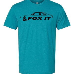 May include: Teal t-shirt with a black graphic of a car and the text "FOX IT". The graphic is a side profile of a classic car. The shirt is made of a soft material.