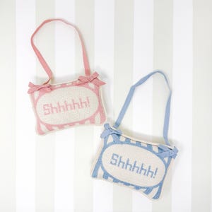 May include: Two fabric door hangers with a striped design and the word "Shhhhh!" embroidered in a white oval. One hanger is pink and the other is blue.