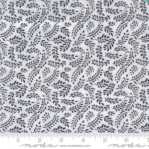 May include: White fabric with a black repeating pattern of small, stylized leaves. The fabric is marked with a ruler in inches.