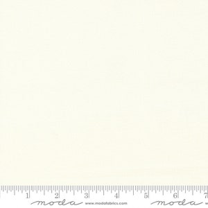 May include: A plain white fabric with a subtle texture. The fabric is measured in inches with the text "moda" printed on the ruler.