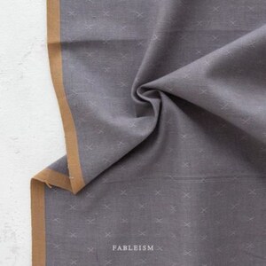 May include: Gray fabric with a subtle crosshatch pattern and a tan border. The fabric is folded in half and the border is visible on the edge.