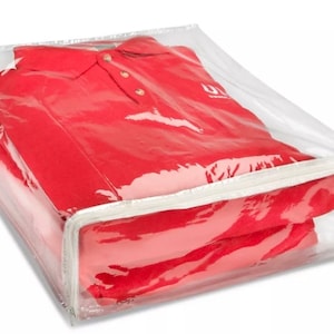 May include: A clear plastic storage bag with a zipper closure, containing two red polo shirts. The bag is designed to protect and store clothing.
