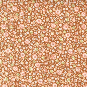May include: A brown fabric with a repeating pattern of small white, pink, and green flowers.