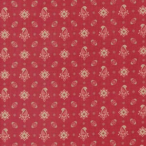 May include: Red fabric with a repeating pattern of paisley and floral designs in beige. The paisley shapes have a curved top and a teardrop shape. The floral designs are four-petaled with a small center. Small oval shapes are scattered throughout.