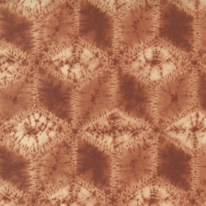 May include: A brown fabric with a repeating pattern of light brown circles with a darker brown center. The fabric has a textured surface.