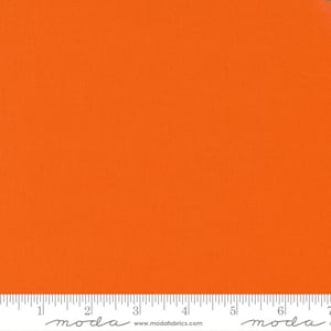 May include: Solid orange fabric with a textured surface. The fabric is a vibrant shade of orange and is suitable for various crafting projects. A ruler is at the bottom of the image.