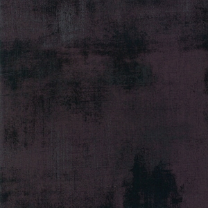 May include: A dark gray and black textured fabric with a subtle sheen. The fabric has a slightly distressed look, with a hint of purple in the background.